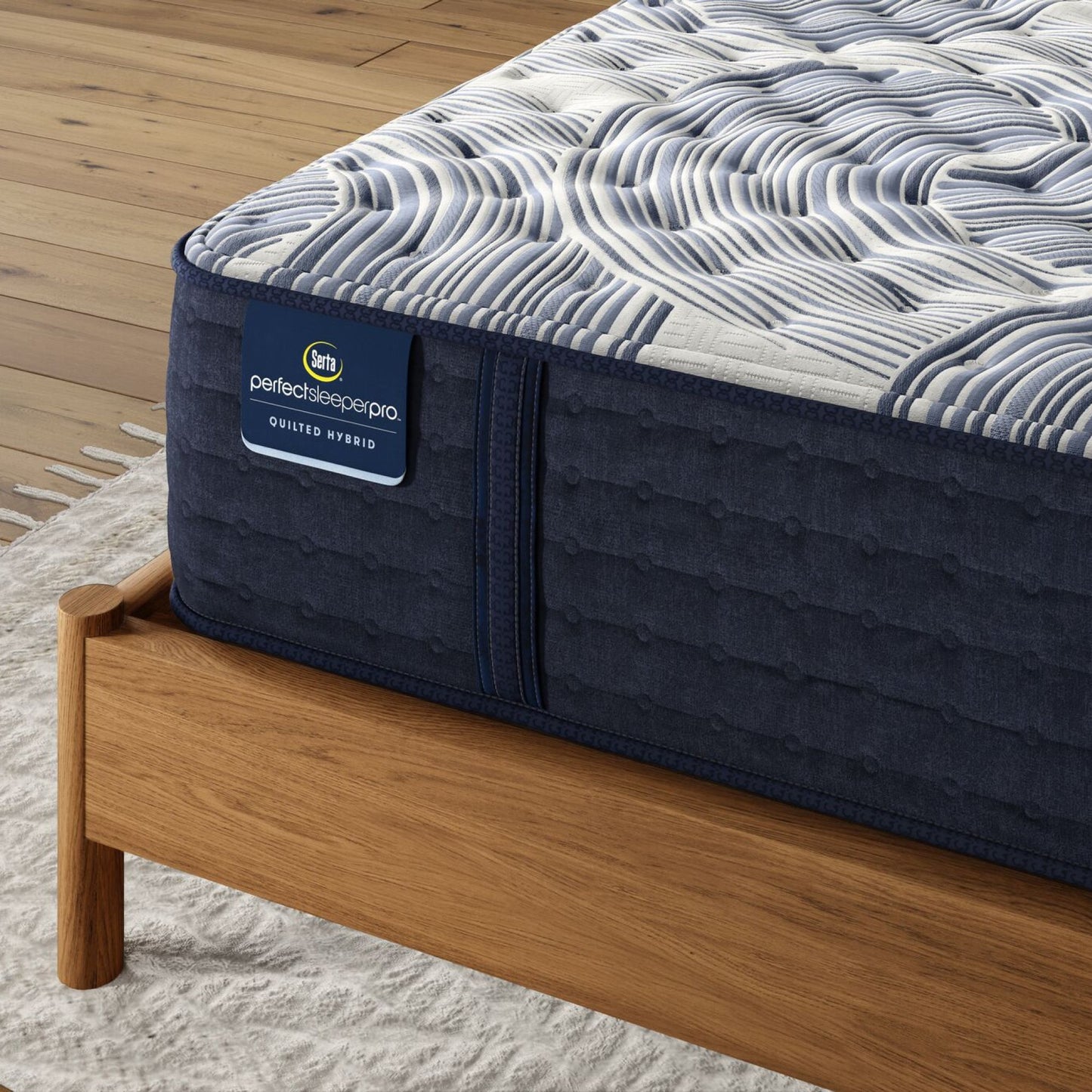 Corner of Perfect Sleeper Pro Geneva Firm mattress sitting in a brown bedframe || Level: Level 2 || Feel: Firm