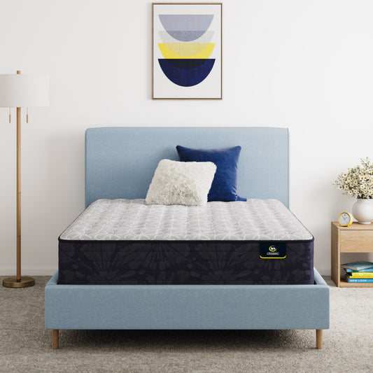 Serta Classic Clarks Hill Mattress on a bed with a blue headboard and decorative pillows in a bedroom setting.