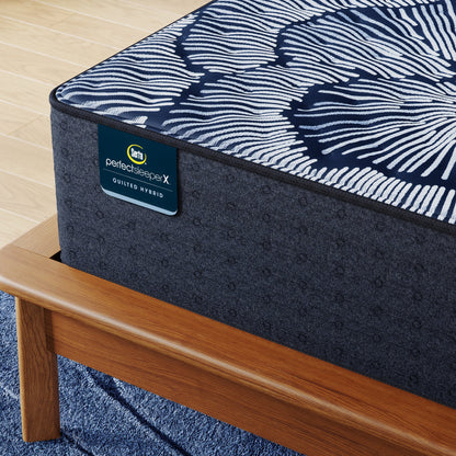 Corner of Perfect Sleeper X Quilted Hybrid Excelled Extra Firm Mattress sitting in a brown bedframe || feel: Extra Firm || level: Level 1
