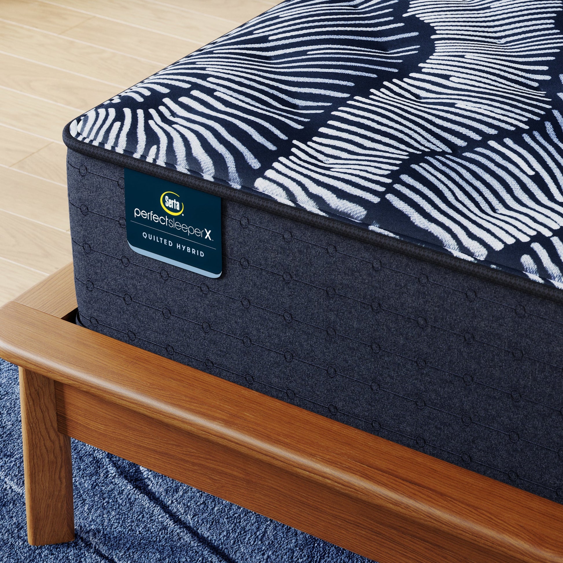 Corner of Perfect Sleeper X Quilted Hybrid Knox Plush Mattress sitting in a brown bedframe || feel: Plush || level: Level 1