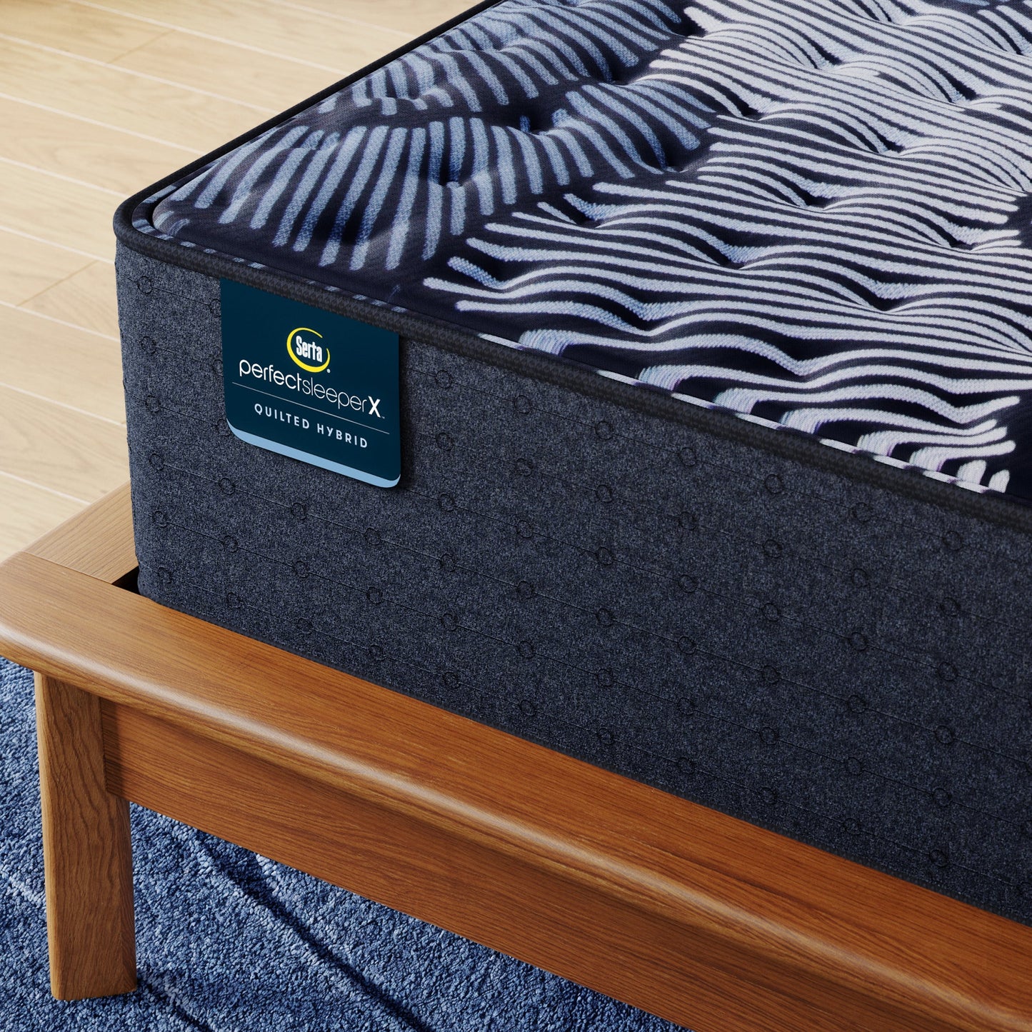 Corner of Perfect Sleeper X Quilted Hybrid Max Medium Mattress sitting in a brown bedframe || feel: Medium || level: Level 2