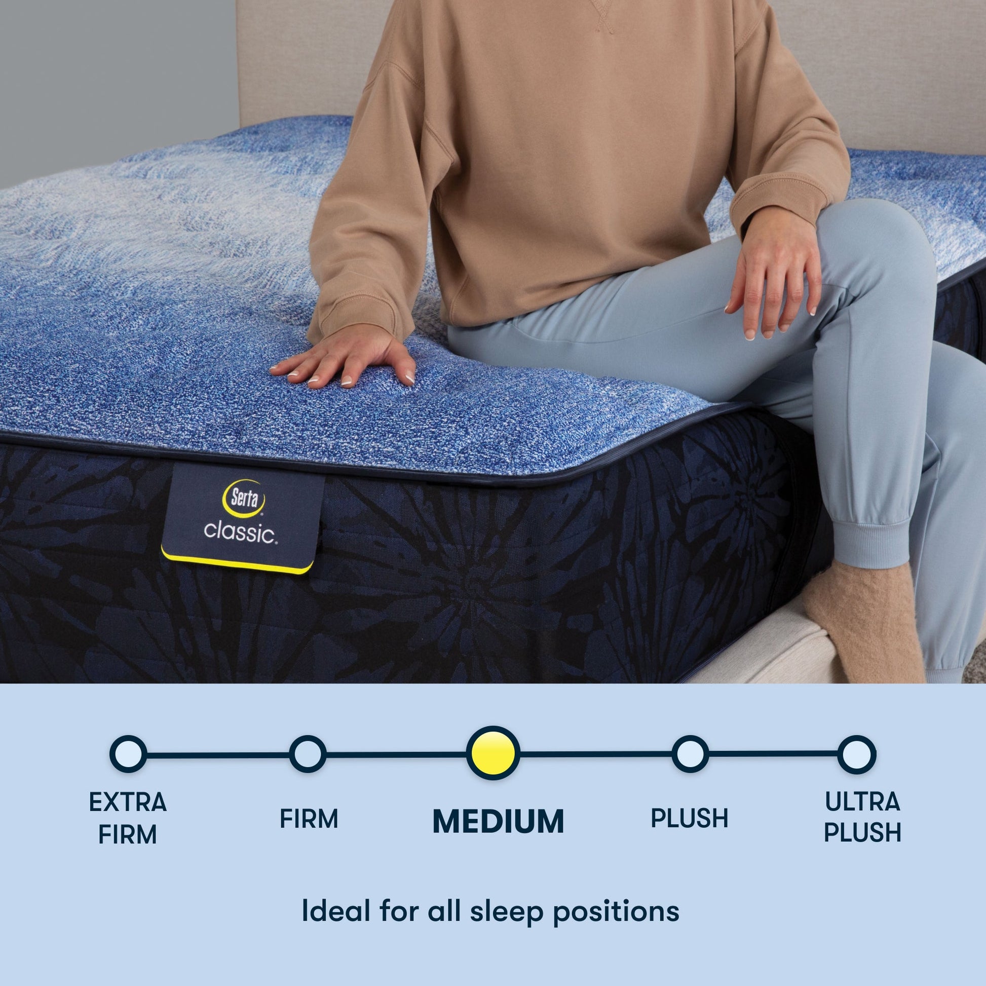 Woman sitting on a Serta classic medium mattress with her right hand placed on the mattress ||feel: medium ||level: enhanced